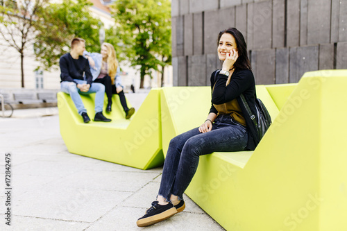Photography Young woman sitting in the city and use a mobile phone