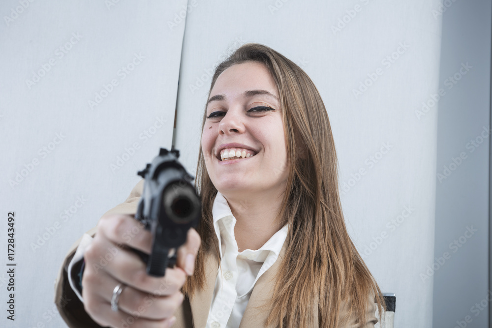 Bella e sorridente segretaria bionda punta una pistola scherzando Bella e sorridente segretaria bionda punta una pistola scherzando
