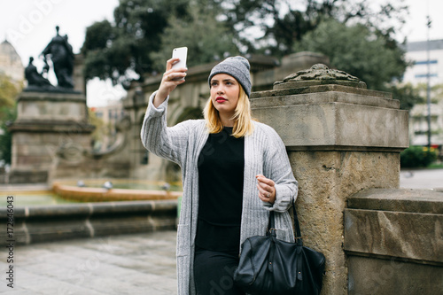 Blonde curvy woman taking a selfie in the city on winter. photo