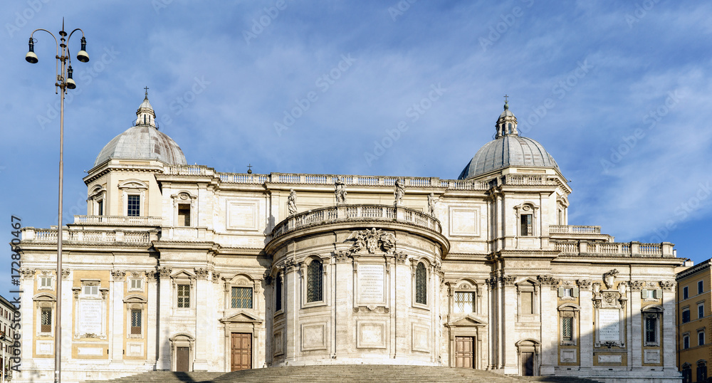 Facade of the papal Basilica called Santa Maria Maggiore, without people in sight and with a blue sky with very light clouds. In the square called 