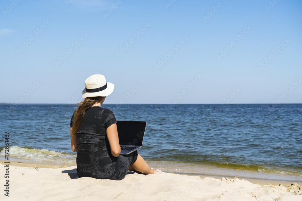 Young girl with a laptop on the sea beach
