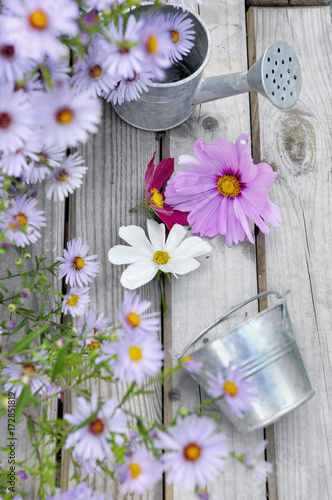 fleurs bleues et mauves et pot en métal sur table bois