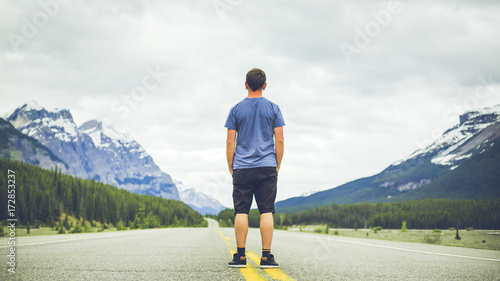man standing on highway in mountains photo
