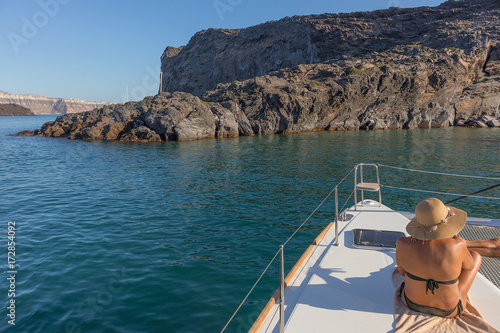 Woman sitting on the bow of boat, santorini greece