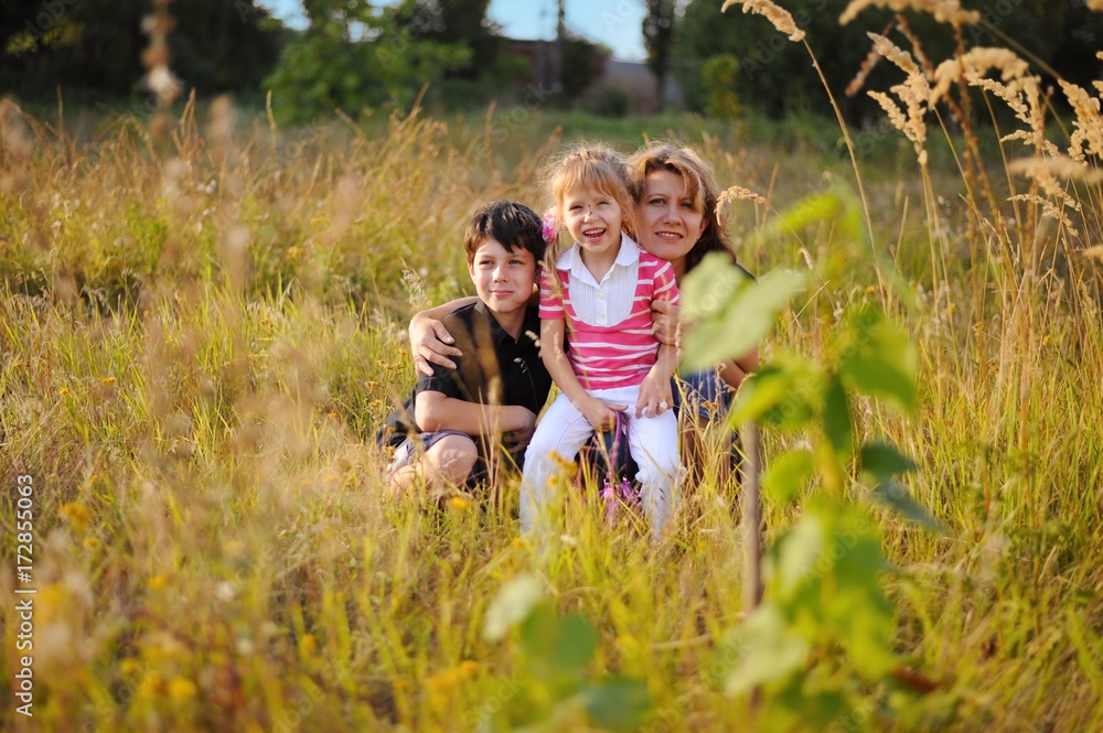 A woman and her children are sitting in high grass