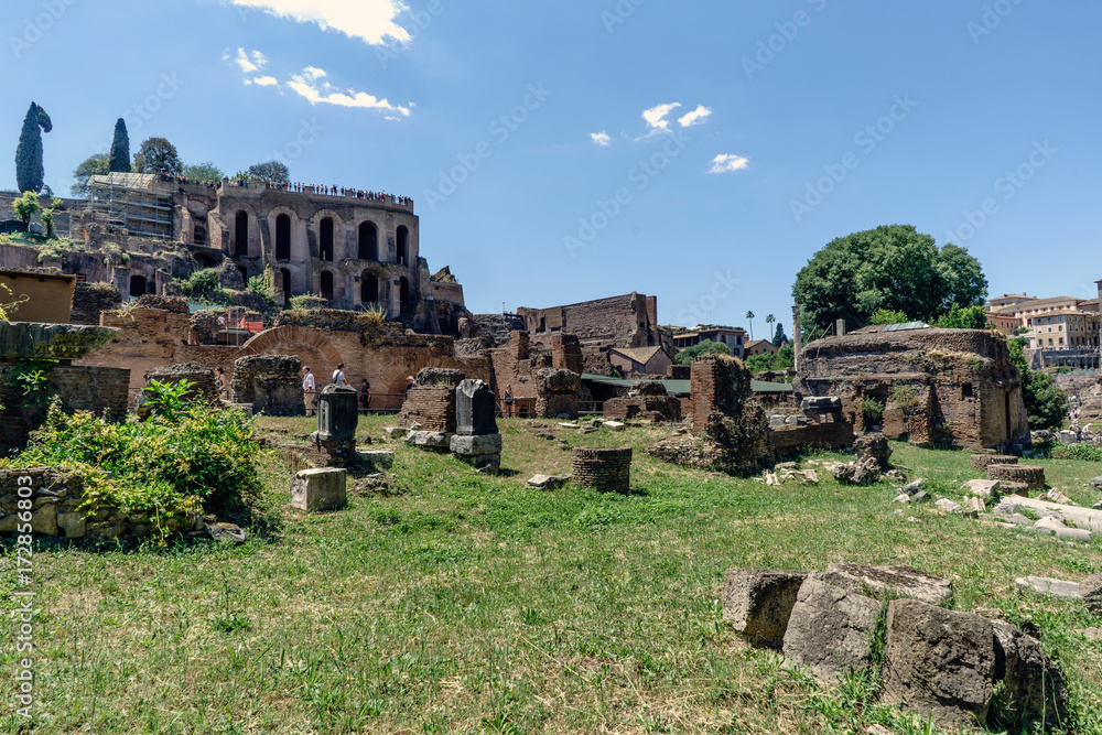 View of the various ruins of the Roman Forum with a very blue sky slightly cloudy without people in sight