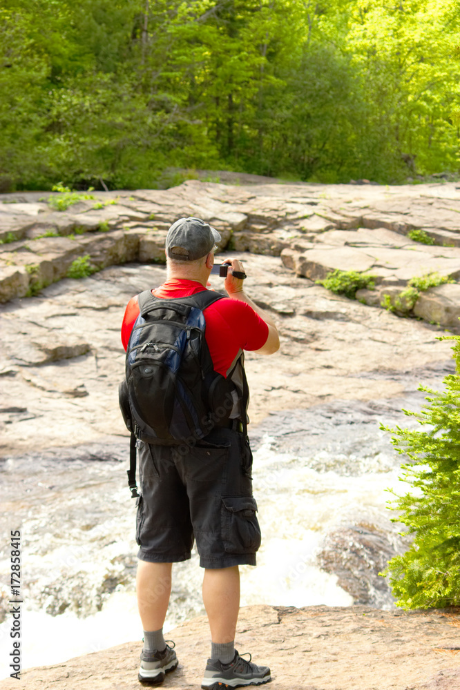 Man standing on a rock and filming the stream