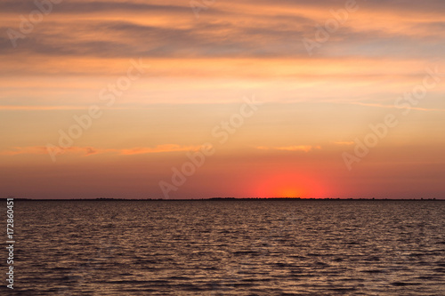 Beautiful scarlet sunset and calm waves on the lake