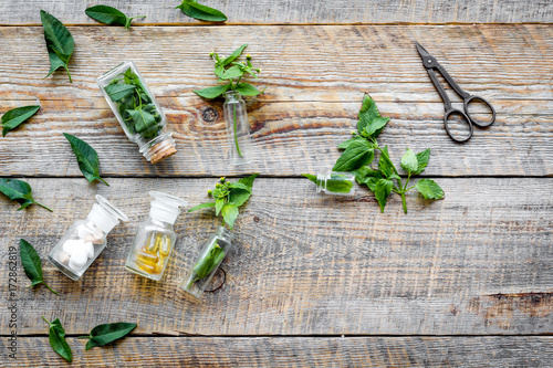 Medicinal herb in bottles on wooden background top view copyspace