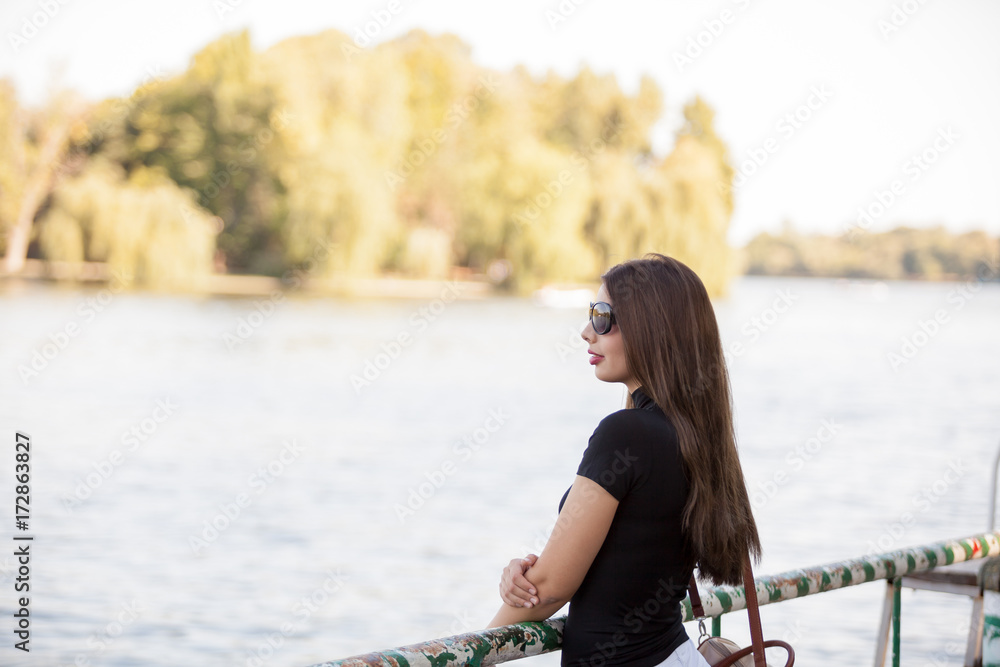Beautiful woman in sunglasses looking at the river. Relax and nature