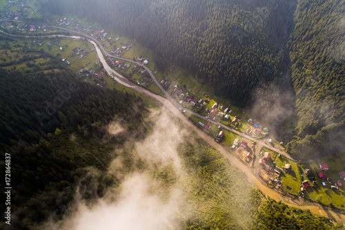 Fototapeta Naklejka Na Ścianę i Meble -  Aerial view of the village in the Carpathian mountains with clouds in the foreground
