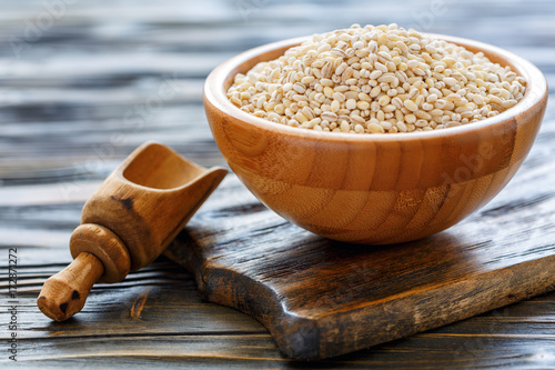 Fotografi Dry pearl barley in a wooden bowl.