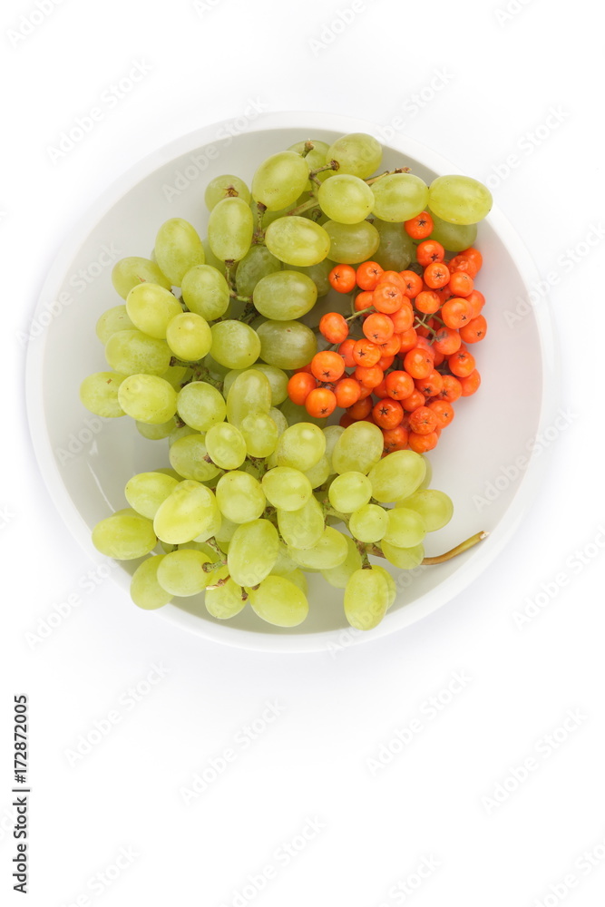 Green grapes and orange ashberry on a white background on a plate in minimalism style Green grapes and orange ashberry on a white background on a plate in minimalism style