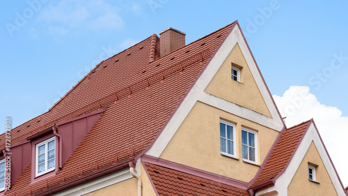 Haus mit Spitzdach und Giebel vor blauem Himmel