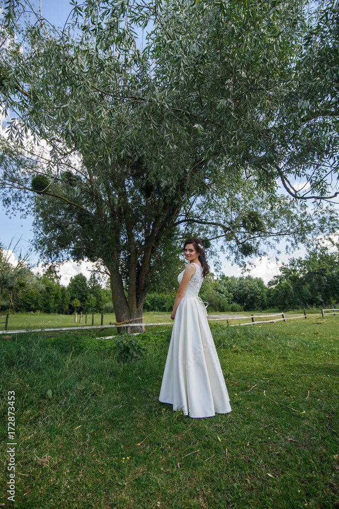 Beautiful bride outdoors on the meadow on a wedding day. Joyful moment of happiness