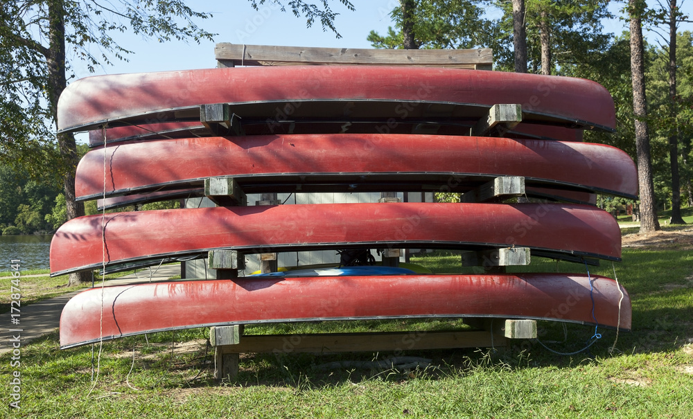Faded and weathered red rental canoes in park setting. Faded and weathered red rental canoes in park setting.