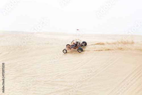 A sand rail speeding along the ridge of a sand dune photo