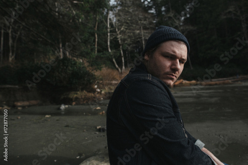 Mid 30's man looking grimly at camera on beach