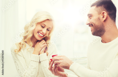 happy man giving engagement ring to woman at home