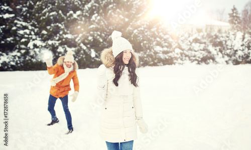 happy couple playing snowballs in winter