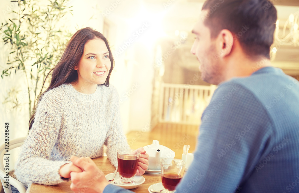 happy couple with tea holding hands at restaurant