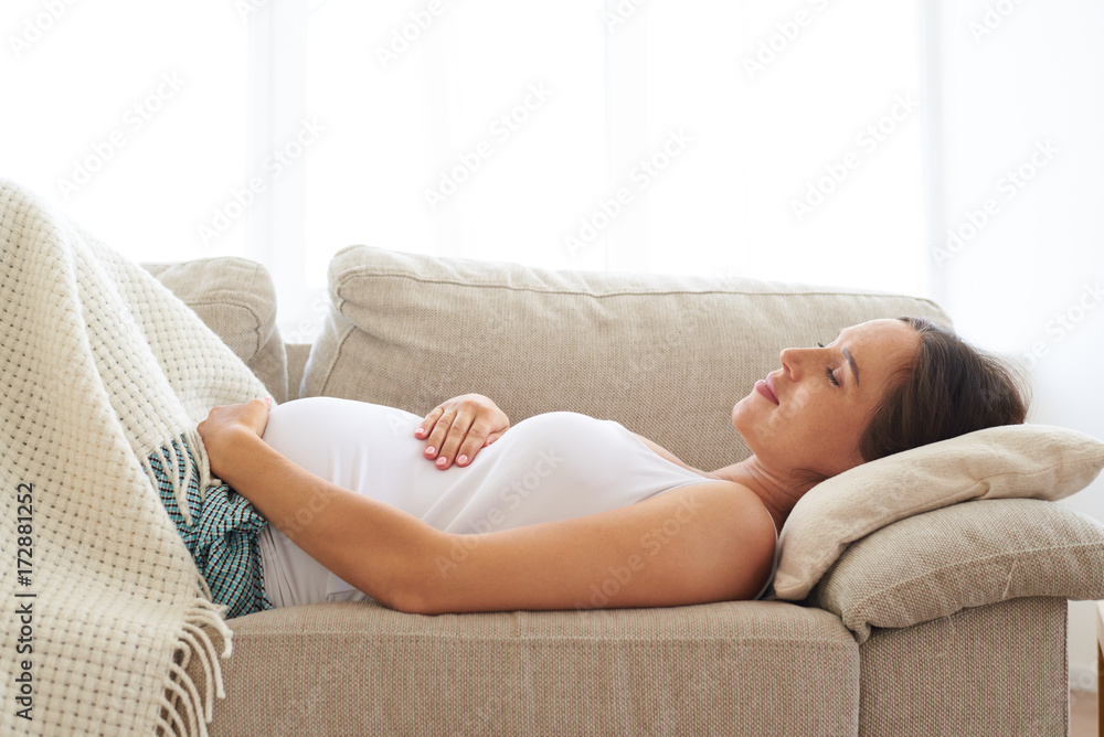 Pregnant woman embracing belly while sleeping on back Pregnant woman embracing belly while sleeping on back
