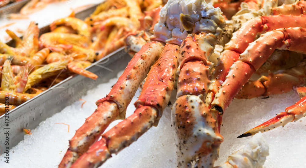 fresh crab legs on ice among shrimps at spanish fish market
