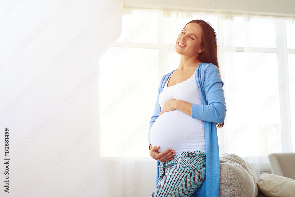 Pregnant woman enjoying warm sunset light at home