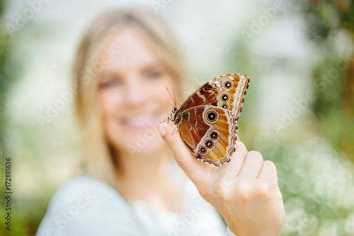 Young Blonde Woman Holding Orange Butterfly On Tip Of Finger photo