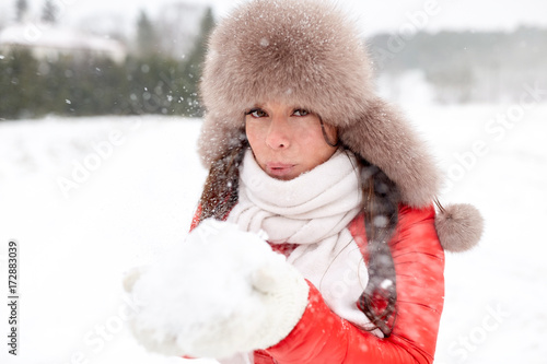 happy woman with snow in winter fur hat outdoors