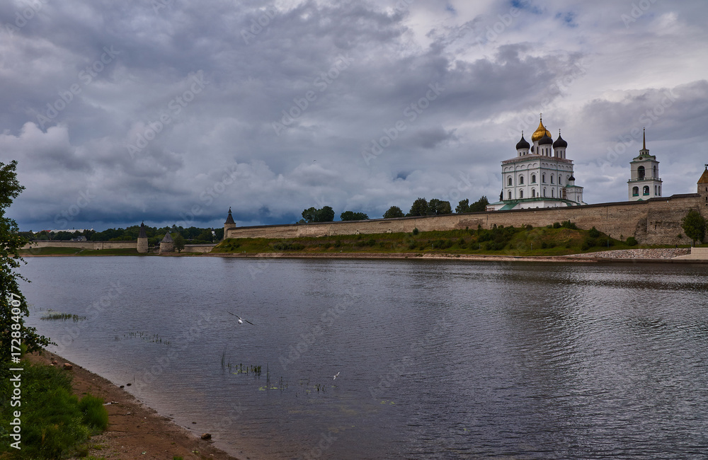 Kremlin of Pskov. The view from the river Great/Summer, evening. The sky is covered with clouds. A gull flies over the river. On the opposite bank is the Pskov Kremlin. Russia, Pskov region, landscape