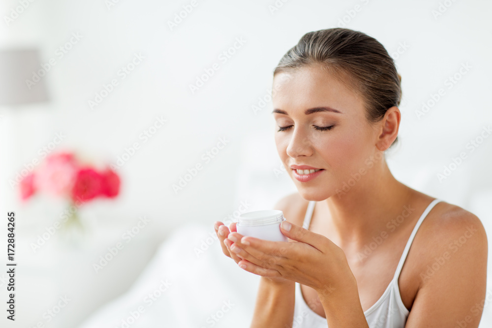 close up of happy woman holding and smelling cream close up of happy woman holding and smelling cream