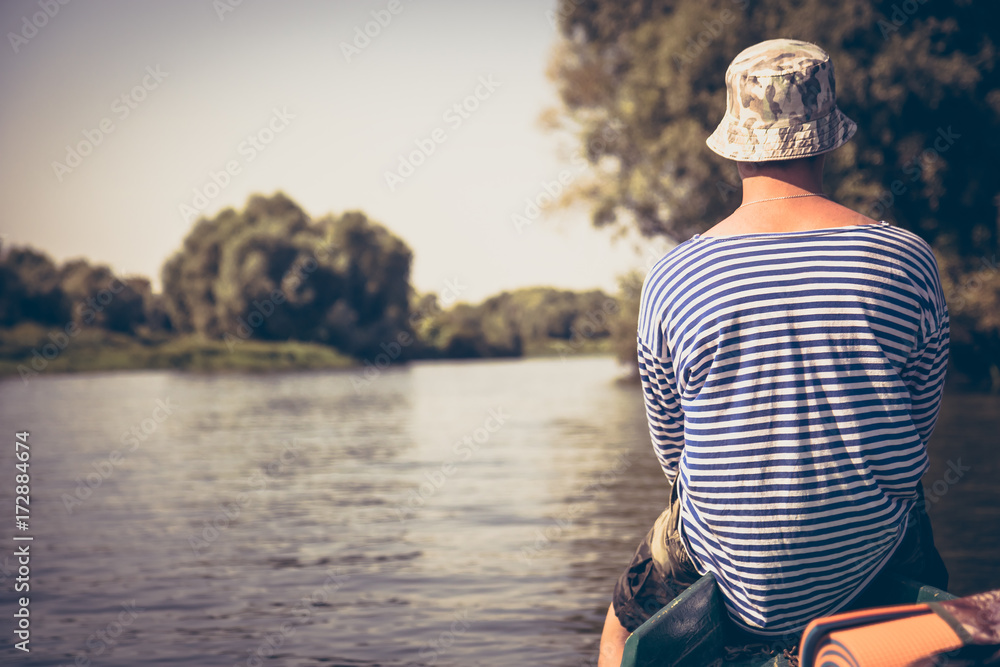 Pensive young man traveling on boat and looking on beautiful scenery  during summer camp holidays
