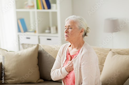 senior woman suffering from heartache at home
