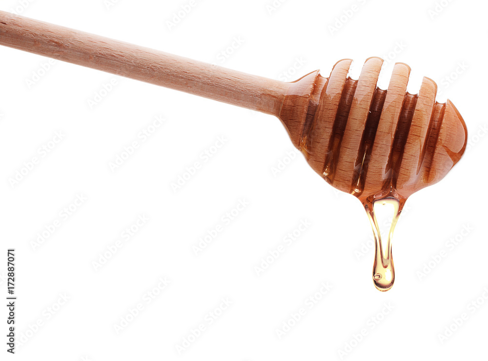 Honey dripping from a wooden honey dipper isolated on white background cutout Honey dripping from a wooden honey dipper isolated on white background cutout