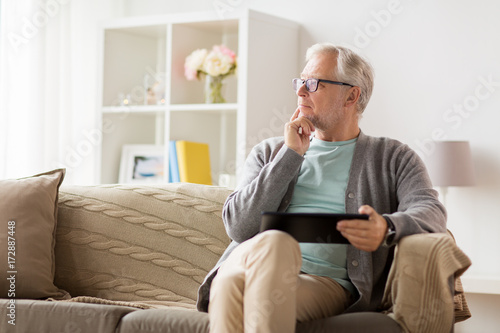 senior man with tablet pc sitting on sofa at home
