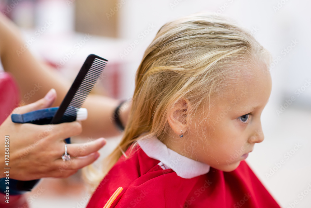 A little girl is done with a hairstyle in a beauty salon.