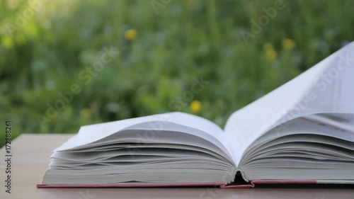 an open book on the garden table, the wind turns the pages