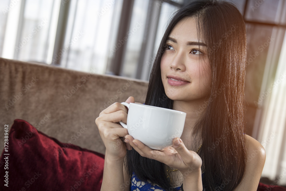 Beautiful Asian girl with cup of cofee mocha drinking in luxury home with sunlight in windows. Copy space for text. Beautiful Asian girl with cup of cofee mocha drinking in luxury home with sunlight in windows. Copy space for text.
