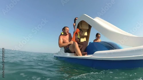 Dad pulls his son out of the sea into the catamaran photo