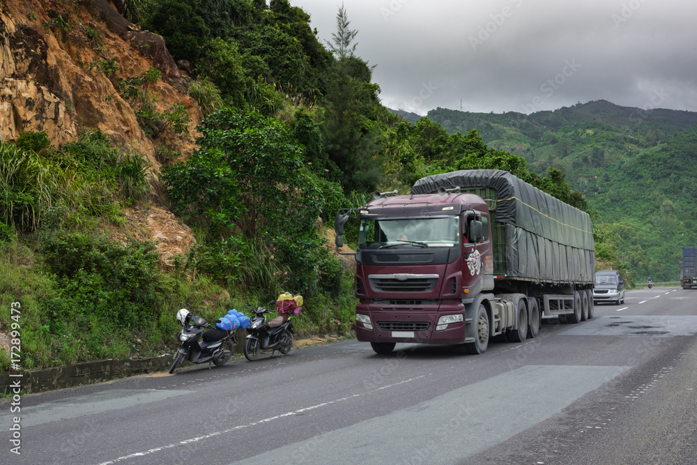 Vietnam Pass, a mountain pass, a truck drives two motorcycles traveling along a serpentine road.