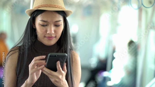 Woman using smartphone to connect to her friend online in skytrain.