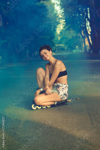 Stylish woman in skates with colored smoke photo