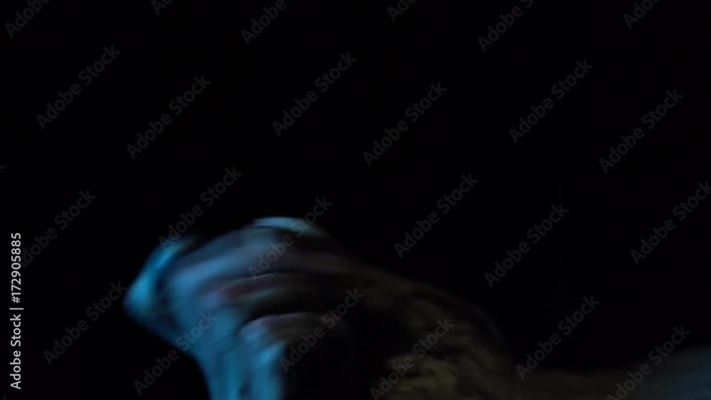 A close-up dirty zombie hand holds and rotates two eyes on a black background in a dark room. Artificial eyeballs look at the camera. A close-up dirty zombie hand holds and rotates two eyes on a black background in a dark room. Artificial eyeballs look at the camera.
