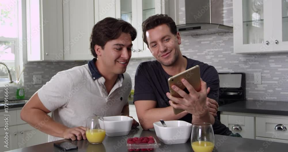 Tilt shot of male couple using tablet computer at breakfast, shot on R3D Tilt shot of male couple using tablet computer at breakfast, shot on R3D