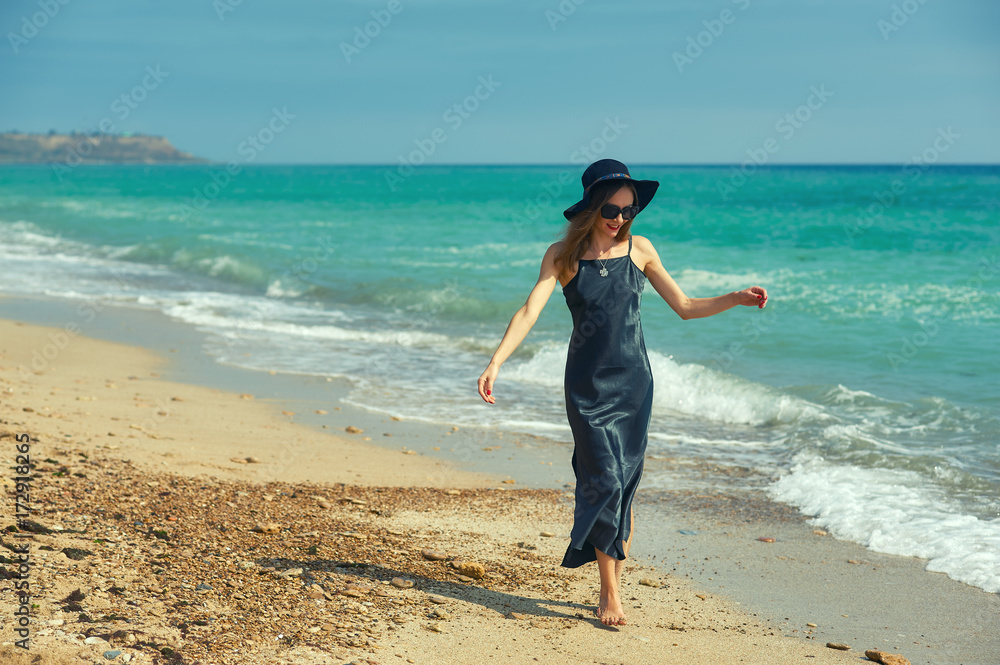 Young woman in evening dress walking along the beach