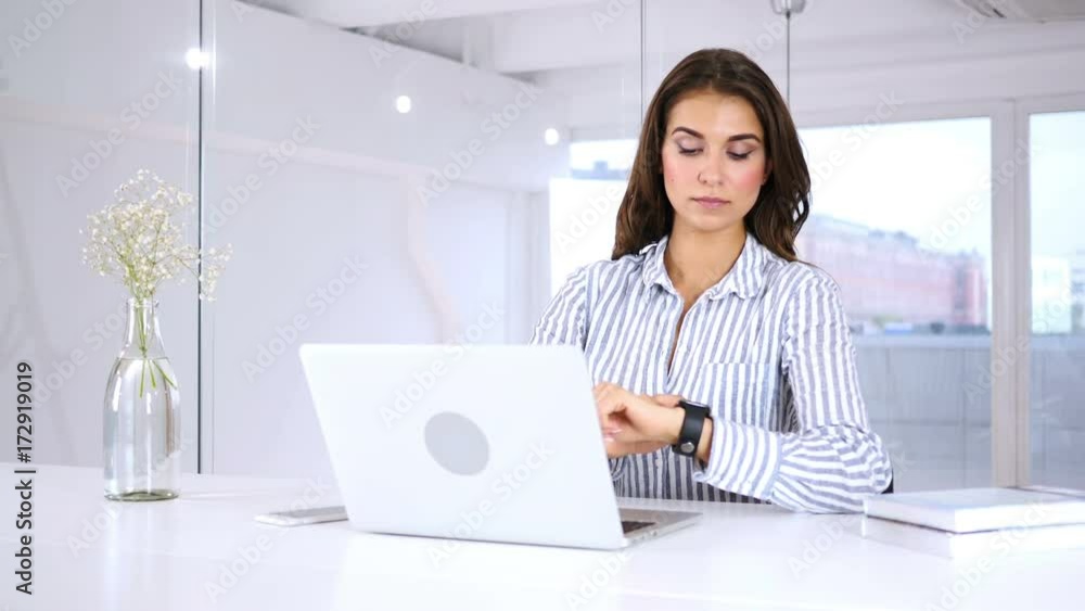 Young Woman Using Smartwatch, Sitting in Office Young Woman Using Smartwatch, Sitting in Office