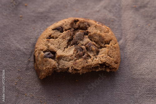 Closeup chocolate chips cookies with bite on brown background