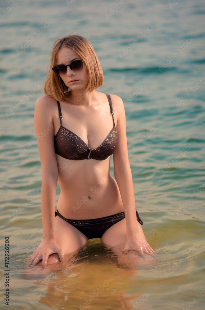 Sexy caucasian tall young woman with glasses and a braun swimsuit posing in  the water Stock Photo | Adobe Stock