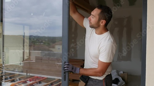 handsome young man installing bay window in a new house construction site